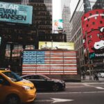 Dynamic view of Times Square with iconic billboards and yellow taxi in New York City.